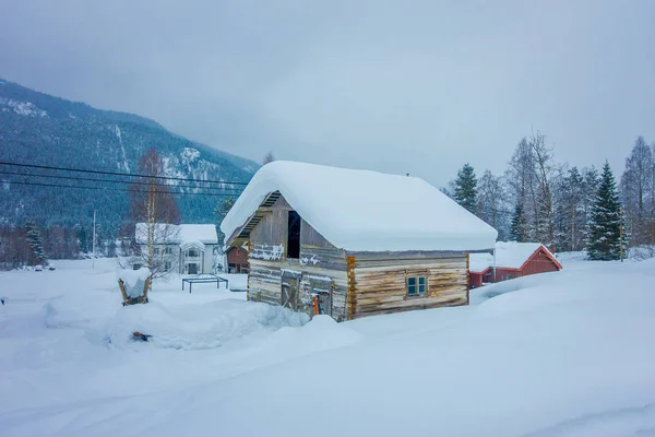 Вид традиционных деревянных домов, покрытых снегом, на потрясающем природном фоне в Норвегии — стоковое фото