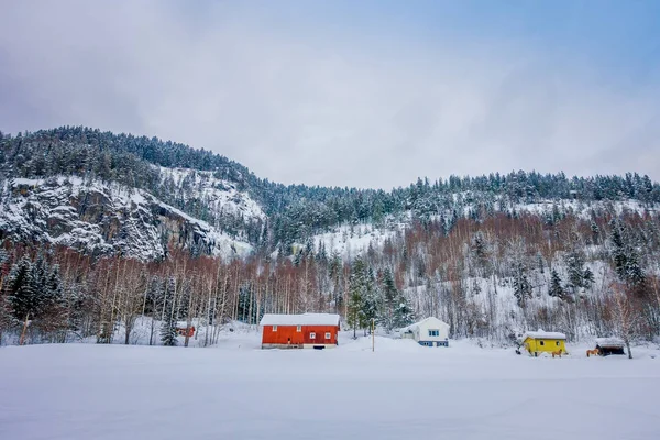 Increíble vista al aire libre de las tradicionales casas rojas de montaña noruegas de madera cubierta de nieve en el techo en un impresionante fondo natural en Noruega — Foto de Stock