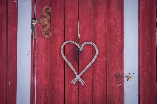 Primo piano del cuore fatto di rami appesi a una porta rossa in una stagione invernale in Norvegia — Foto Stock