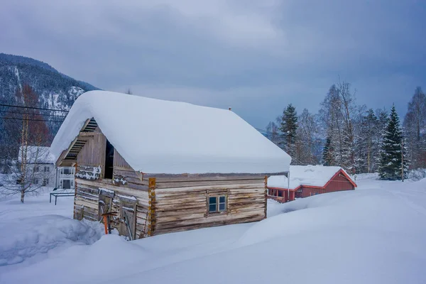 Vista de casas de madeira tradicionais cobertas de neve em fundo deslumbrante natureza e enorme montanha atrás na Noruega — Fotografia de Stock