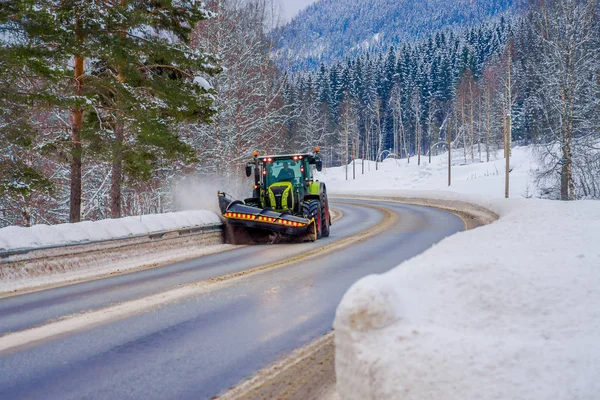 Valdres, Norway - March 26, 2018: Outdoor view of snow-removing machine cleans the street of the road from the snow in the morning snow-covered trees and roads in Norway — Stock Photo, Image