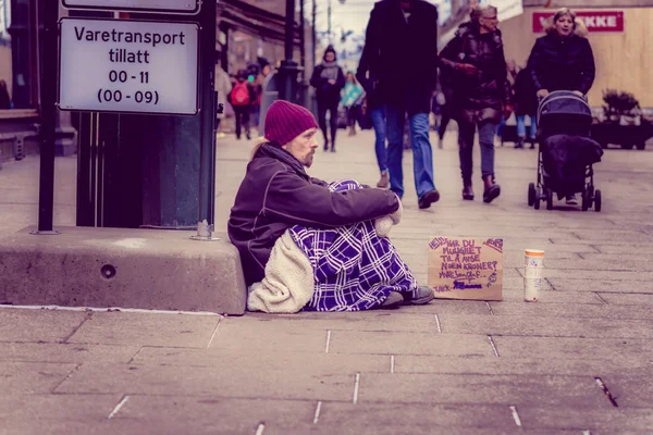 OSLO, NORUEGA - 26 de marzo de 2018: Vista al aire libre de un indigente no identificado sentado en el suelo pidiendo dinero en las calles de la ciudad de Oslo — Foto de Stock