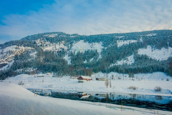 Verbazingwekkend uitzicht op de buitenlucht van vele houten huizen dicht bij een prachtig meer bedekt met sneeuw en ijs in het bos tijdens de winter in Noorwegen — Stockfoto