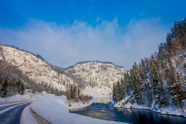 Outdoor view of winter road covered with heavy snow and ice in the forest and small river at one side of the road — Stock Photo, Image