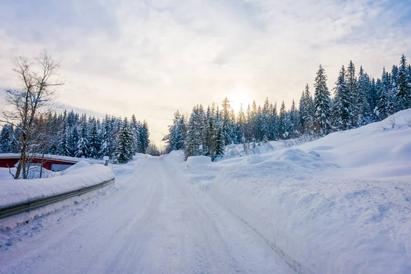 Vista al aire libre de la carretera de invierno cubierta de nieve pesada y hielo en el bosque y una magnífica vista al atardecer — Foto de Stock