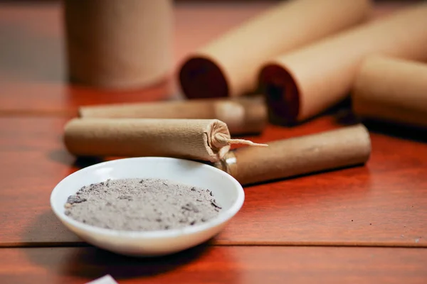 Close up of brown firecrackers close to a white bowl with gunpowder, over a wooden table — Stock Photo, Image