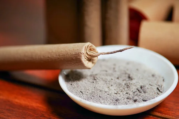 Close up of selective focus of brown firecrackers close to a white bowl with gunpowder, over a wooden table — Stock Photo, Image