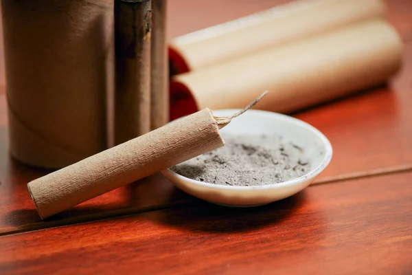 Close up de fogo de artifício marrom perto de uma tigela branca com pólvora, sobre uma mesa de madeira — Fotografia de Stock