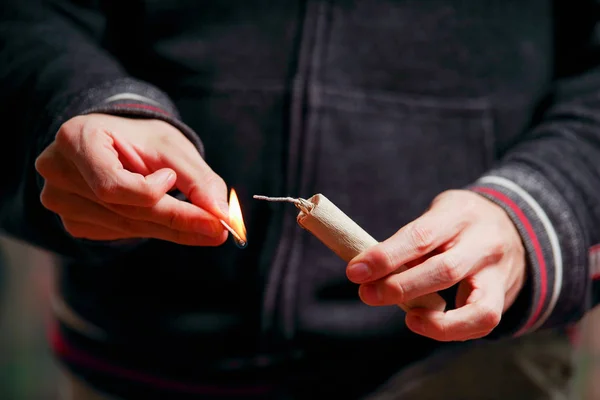 Närbild av mannen hand belysning upp en smällare i en burred bakgrund — Stockfoto