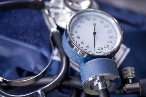 Primo piano del tensiometro su una tavola metallica con uno stetoscopio, concetto medico — Foto Stock
