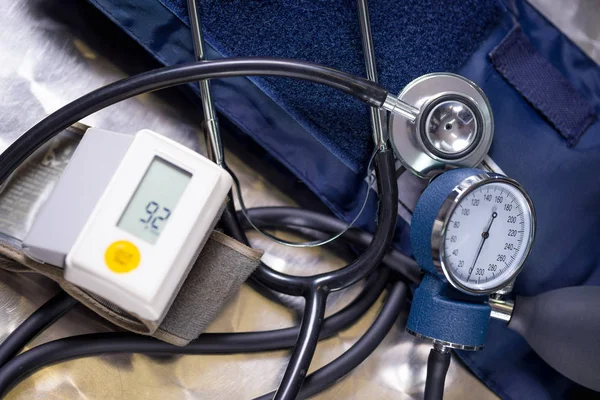 Vista superior del monitor de presión arterial de la muñeca que muestra la presión arterial normal, con un estetoscopio y tensiómetro sobre una mesa metálica, concepto médico —  Fotos de Stock