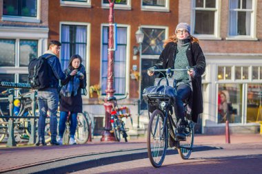 Amsterdam, Hollanda, Mart, 10 2018: Amsterdam'ın tarihi bölümünde bisiklet sürme kimliği belirsiz bir kadın
