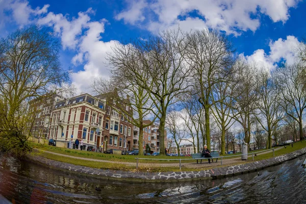 Amsterdam, Niederlande, 10. März 2018: Außenansicht der Menschen im Park mit trockenen Bäumen in einem Park am Flussufer an den Kanälen von amsterdam, ist die Hauptstadt der Niederlande mit sonnigem Tag — Stockfoto