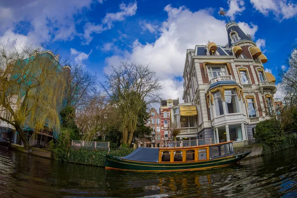 Άμστερνταμ, κάτω χώρες, Μάρτιος, 10 2018: εξωτερική θέα των ξηρών δέντρων στο ποτάμι στα κανάλια του Άμστερνταμ Ολλανδία, με μια βάρκα στο νερό με όμορφη ηλιόλουστη μέρα — Φωτογραφία Αρχείου