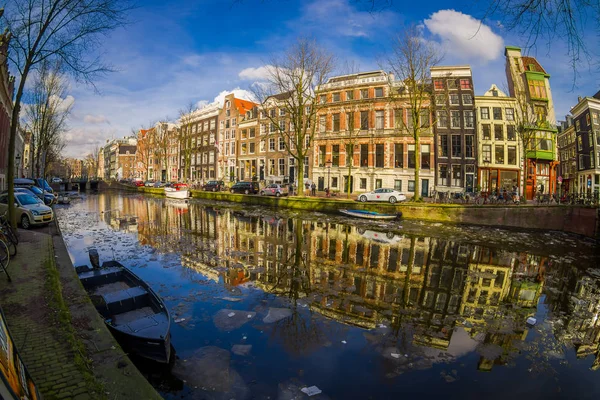 AMSTERDAM, PAESI BASSI, 10 MARZO 2018: Vista esterna di case e barche sul canale di Amsterdam. Foto mattutina di case colorate in stile olandese con riflesso in acqua — Foto Stock