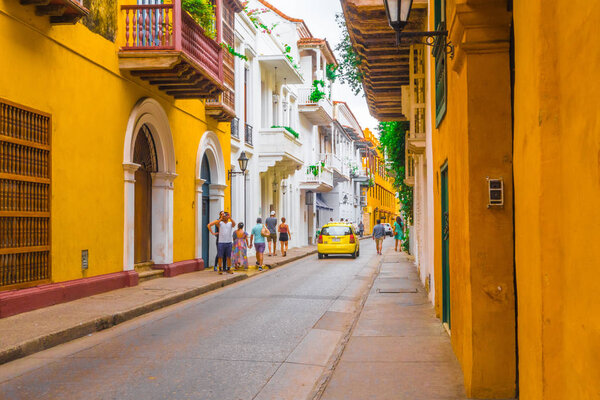 CARTAGENA, COLOMBIA, OCTOBER, 30, 2017: Unidentified people walking and taking pictures in Cartagena city street with colorful building of Cartagena Walled City.