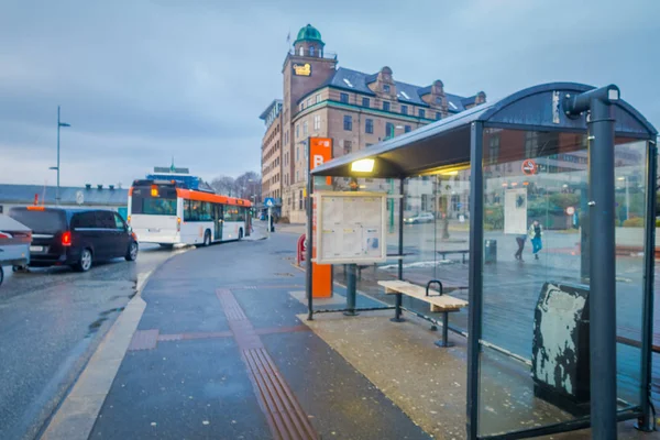 Bergen, Noruega - 03 de abril de 2018: Vista ao ar livre de uma parada de ônibus turva com alguns transportes públicos nas ruas da cidade de Bergen, com edifícios situados ao longo do lago — Fotografia de Stock