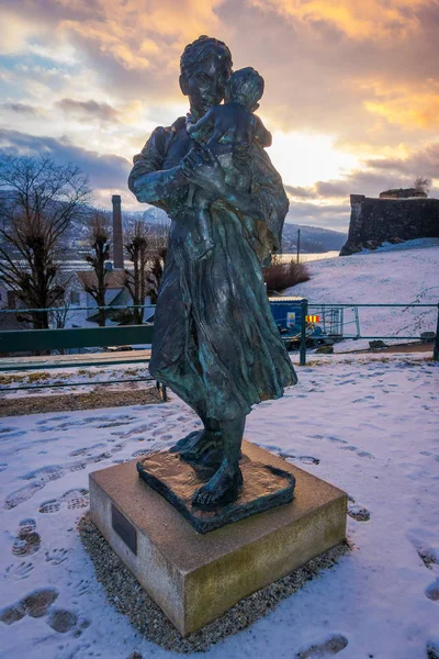 BERGEN, NORUEGA - 03 DE ABRIL DE 2018: Vista al aire libre de la estatua de la mujer y el bebé en el puerto de Bergen, durante una puesta de sol — Foto de Stock
