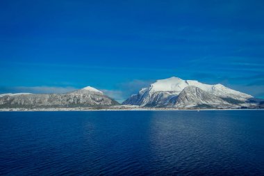 Mavi gökyüzünde bir yolculuk sırasında Hurtigruten kar ile kaplı büyük Dağı'nın kıyı sahnelerin muhteşem manzara
