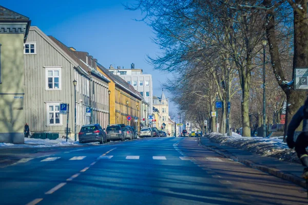 TRONDHEIM, NORUEGA - 06 DE ABRIL DE 2018: Vista al aire libre de la carretera con algunos coches aparcados alrededor con edificios escandinavos tradicionales a lo largo de Trondheim — Foto de Stock