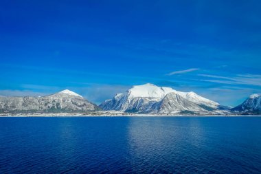 Mavi gökyüzünde bir yolculuk sırasında Hurtigruten kar ile kaplı büyük Dağı'nın kıyı sahnelerin muhteşem manzara
