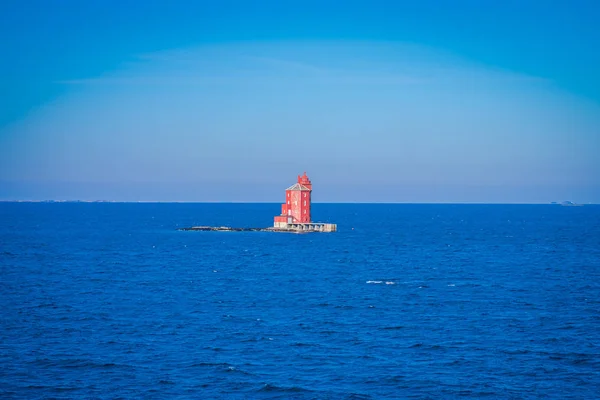 Outdoor view of the red lighthouse on the Norwegian sea over a rock — Stock Photo, Image
