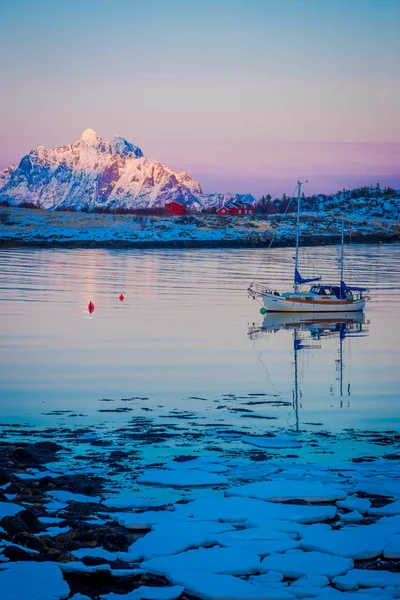 Svolvaer, 罗弗敦群岛, 挪威-2018年4月10日: 在海滩上的冰块的户外景观与一个部分冰冻湖, 船在后面航行 — 图库照片