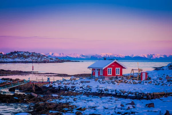 Svolvaer, Lofoten öarna, Norge - 10 April 2018: Utomhus sikt rosa himlen med röda rorbu fiske byggnad på en sten i Lofoten öarna, Svolvaer — Stockfoto