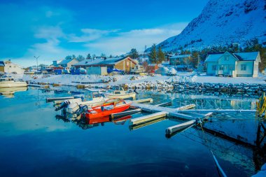 Henningsvaer, Norveç - 04 Nisan 2018: Açık bir balıkçı limanı içinde küçük balıkçı tekneleri su Lofoten Adaları dağ yansımasıyla birlikte görünümünü