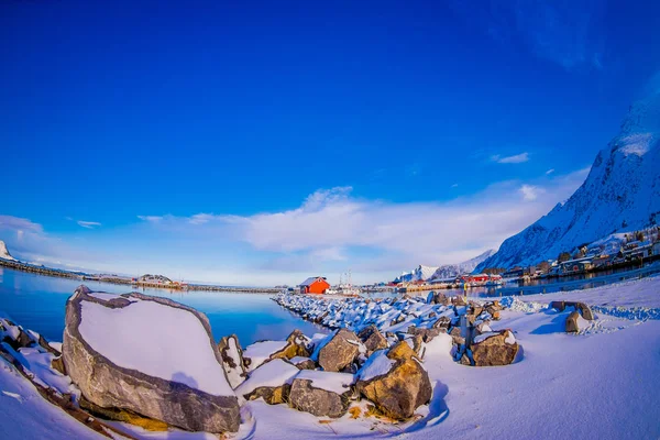 Närbild av bergarter täckta med snö under en vinter station med byggnader bakom i Svolvaer — Stockfoto