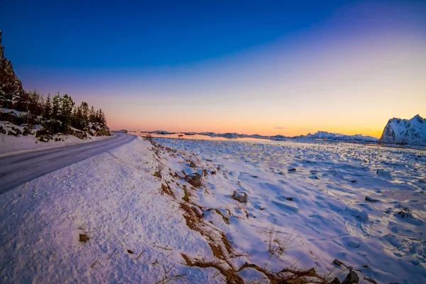 Szabadtéri nézet út szerepelnek a hó és a tengerpart, a befagyott tó egy csodálatos naplemente, télen az északi-sarkkör — Stock Fotó