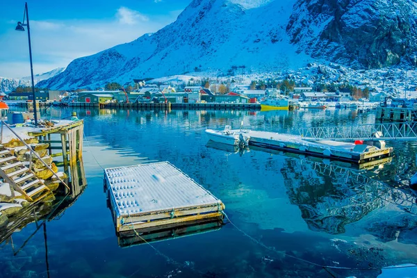 Henningsvaer, Noruega - 04 de abril de 2018: Vista al aire libre del puerto pesquero con estructura flotante de madera y pequeños barcos de pesca en las islas Lofoten — Foto de Stock