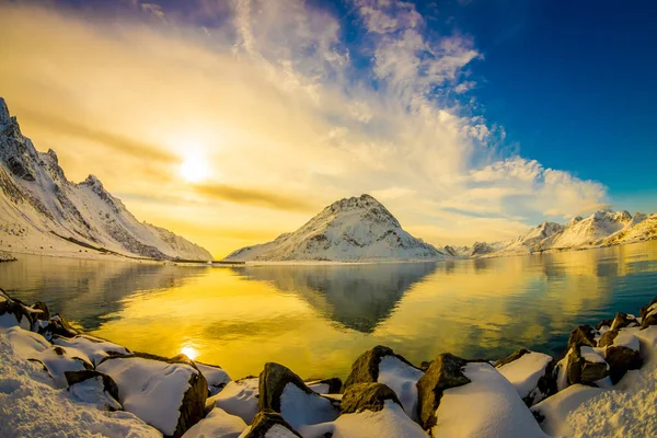 Bela vista panorâmica deslumbrante da montanha refletindo no lago com luz amarelada em Svolvaer, com rochas cobertas de neve — Fotografia de Stock