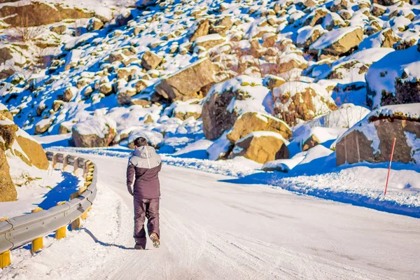 Vista al aire libre de la calle congelada con un hombre no identificado caminando por la carretera, cubierto de nieve durante una temporada de invierno en Skjelfjord en las Islas Lofoten —  Fotos de Stock