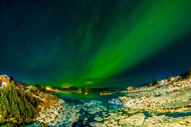 Açık yeşil aurora borealis gökyüzünde görünümünü buz gece ve küçük ve orta ölçekli parçalar sırasında inanılmaz düşük gelgit sırasında donmuş bir gölün üzerinde geride