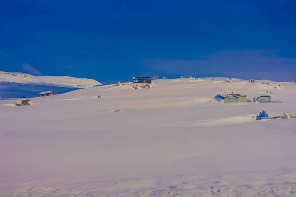 Vista exterior de algunas casas de madera casi cubiertas de nieve durante una fuerte tormenta de nieve, en el área de la montaña Gol —  Fotos de Stock
