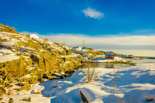 Vista esterna con alcuni edifici nella baia nelle isole Lofoten circondata da montagne innevate e colorata stazione invernale — Foto Stock