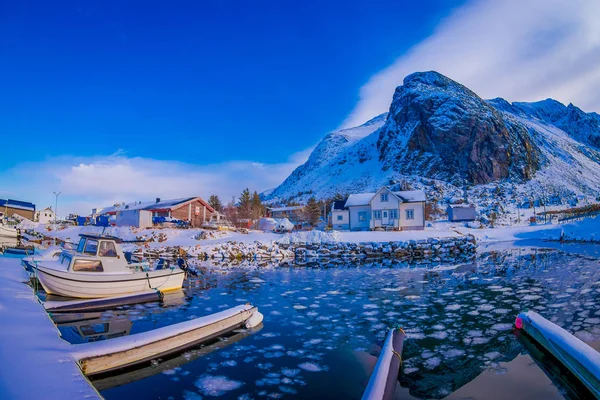 Svolvær, Lofoty, Norwegia - 10 kwietnia 2018: Widok zewnątrz rybackich łodzi w porcie z budynku za i ogromne góry pokryte śniegiem w Svolvær, gminie wyspy Lofoty — Zdjęcie stockowe