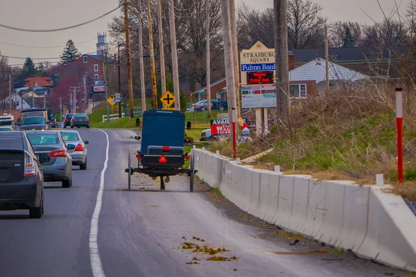 Lancaster, USA - 18. April 2018: Außenansicht der Rückseite eines altmodischen Amish Buggy mit einem Pferd, das auf einer städtischen Straße reitet, die von Autos und Schildern umgeben ist, in der Neuzeit — Stockfoto