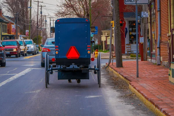 Lancaster, Amerikai Egyesült Államok - április, 18, 2018: Szabadtéri Nézd vissza a régi vágású Amish buggy, a lovaglás, az egyik oldalon a környező városi közúti autók és épületek — Stock Fotó