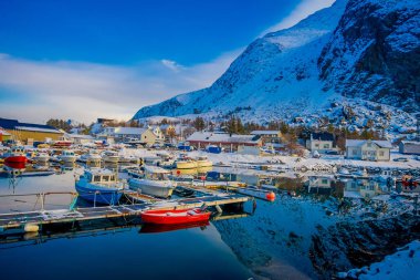 Henningsvaer, Norveç - 04 Nisan 2018: Açık bir balıkçı limanı içinde küçük balıkçı tekneleri su Lofoten Adaları dağ yansımasıyla birlikte görünümünü