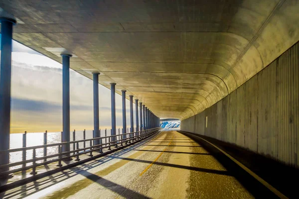 Vista ao ar livre da estrada pelo mar sob uma caminhonete apedrejada com colunas e vista para o mar durante um lindo pôr do sol na ilha Lofoten — Fotografia de Stock
