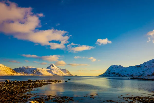 Solnedgång vid Henningsvaer strandlinjen med enorma berg täckta med snö i en vacker blå himmel på Lofoten öarna, Austvagoya — Stockfoto