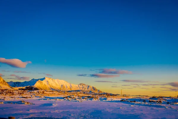 Sunset at Henningsvaer shoreline with huge mountains covered with snow in a gorgeous blue sky on Lofoten Islands, Austvagoya — Stock Photo, Image