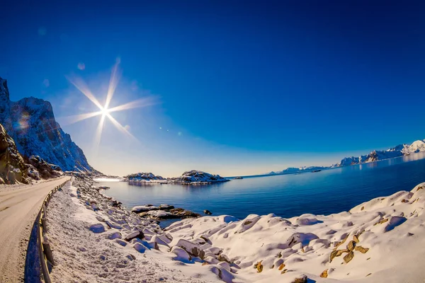 Utomhus utsikt över vägen och havet i sjön i en fantastisk solnedgång med en solen skina i himlen, på vintersäsongen i polcirkeln — Stockfoto