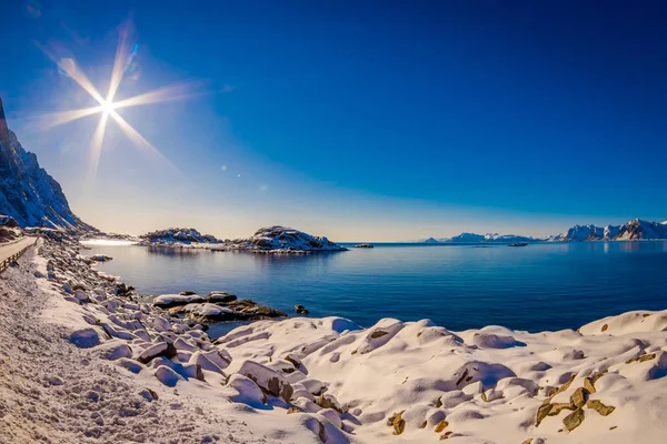 Vista ao ar livre da estrada e beira-mar do lago em um pôr do sol incrível com um sol brilhar no céu, na temporada de inverno no Círculo Ártico — Fotografia de Stock