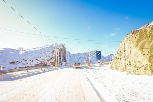 LOFOTEN, NORUEGA, 10 DE ABRIL DE 2018: Vista al aire libre de la calle congelada con un signo informativo de la velocidad de grabación de la cámara y el coche en el camino cubierto de nieve en Skjelfjord en las Islas Lofoten — Foto de Stock