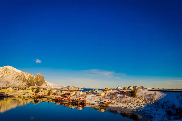 Henningsvaer, Norge - 09 April 2018: Vackra ovanför vyn av träbyggnader med enorma mountaing bakom i Henningsvaer i Lofoten öarna — Stockfoto