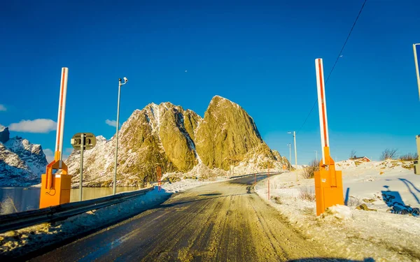 Henningsvaer, Norvegia - 10 aprile 2018: Vista esterna di strada ghiacciata coperta di neve e sistema di controllo situato in strada in una giornata di sole a Henningsvaer — Foto Stock