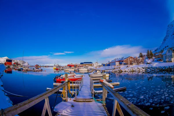 Svolvaer, Lofoten öarna, Norge - 10 April 2018: Utomhus utsikt över träpiren täckt med snö med somes fiskebåtarna i hamnen med byggnader i horizont Svolvaer, Lofoten öarna — Stockfoto